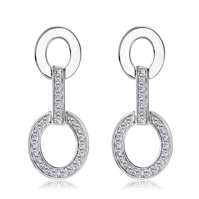 Pair of silver earrings with circular design and clear stones on a white background