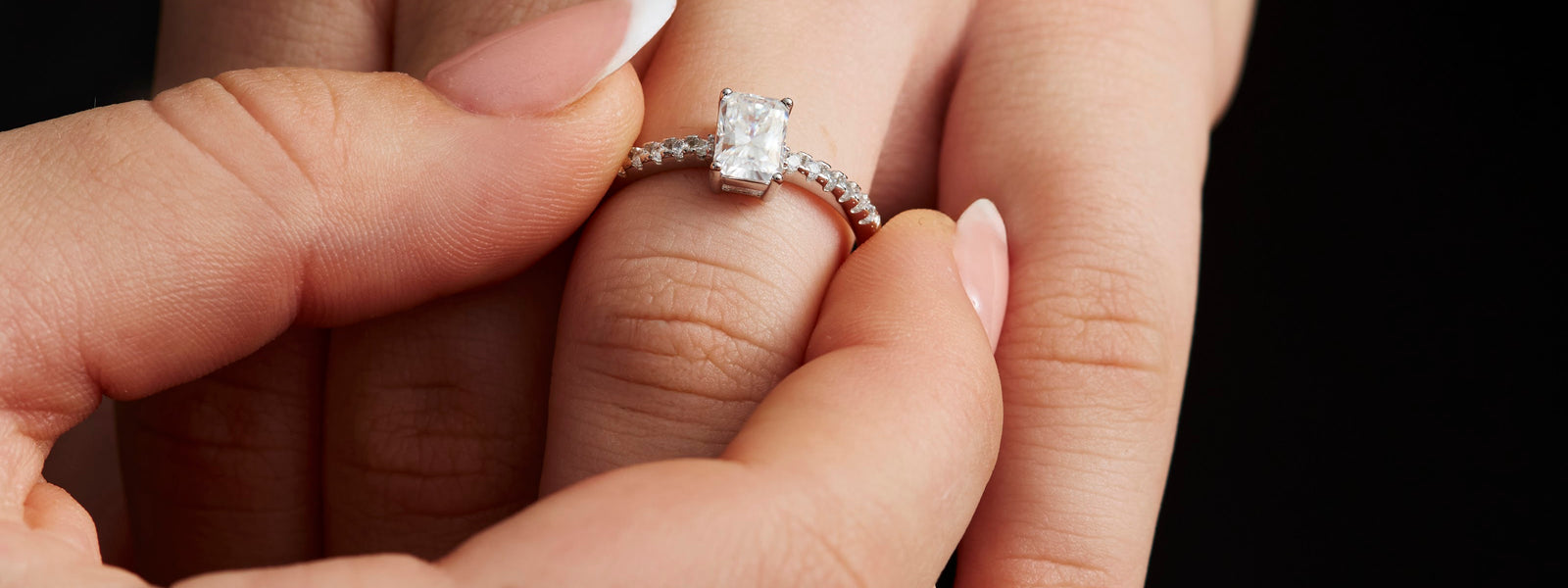 Radiant cut moissanite ring being slipped onto a finger