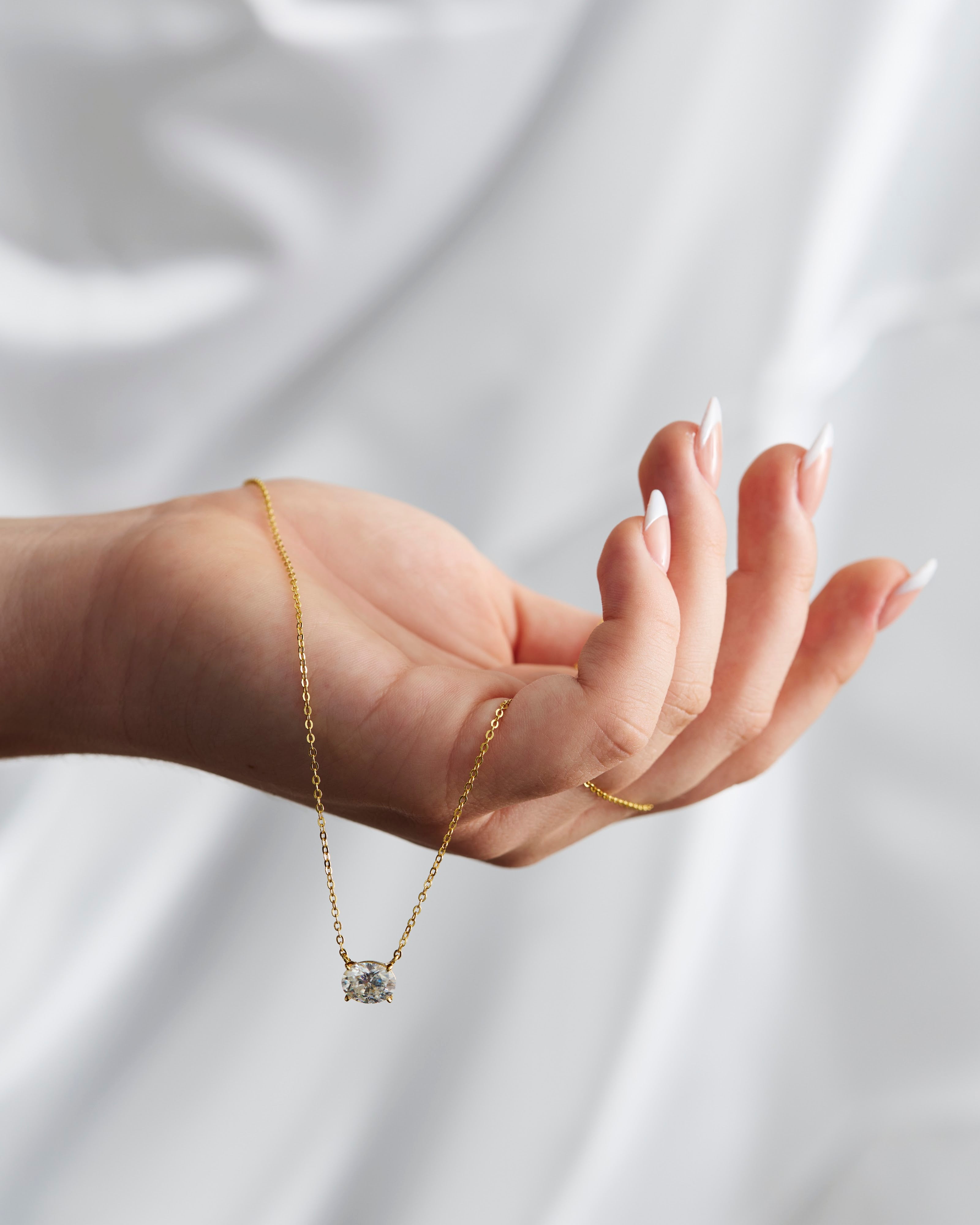 Hand wearing moissanite jewellery on white silk