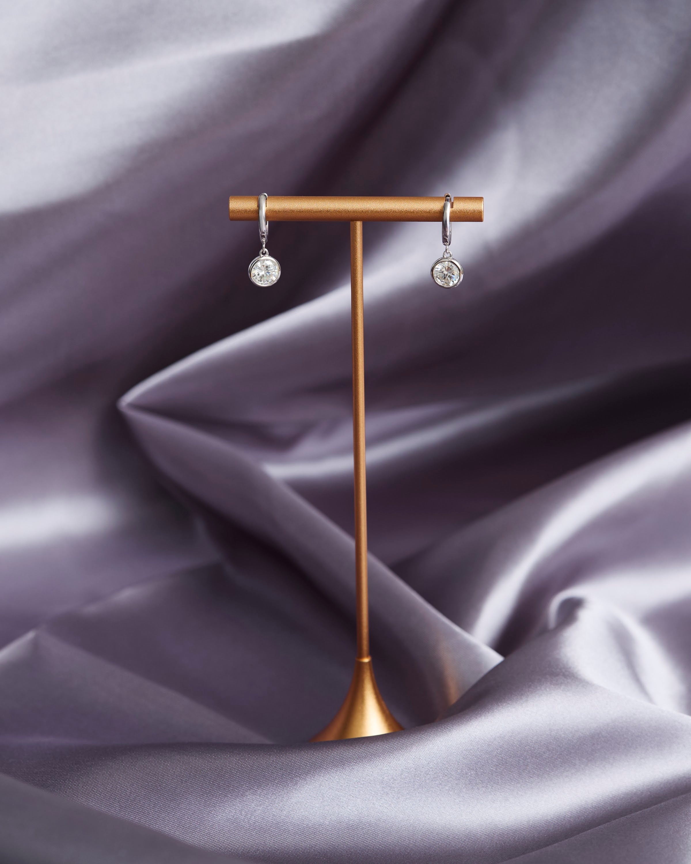 Moissanite earrings displayed on a stand
