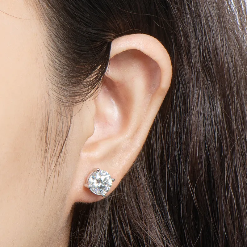 Close-up of an ear wearing a moisanite stud earring with dark hair.