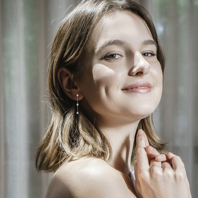 Women wearing Coralie Three stone Bezel danle earring blurred background