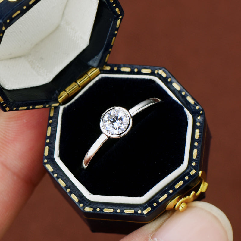 Diamond ring in a decorative black and gold box held by a hand. Prism and Pearl