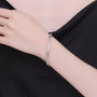 Silver bracelet on a person's wrist against a black background