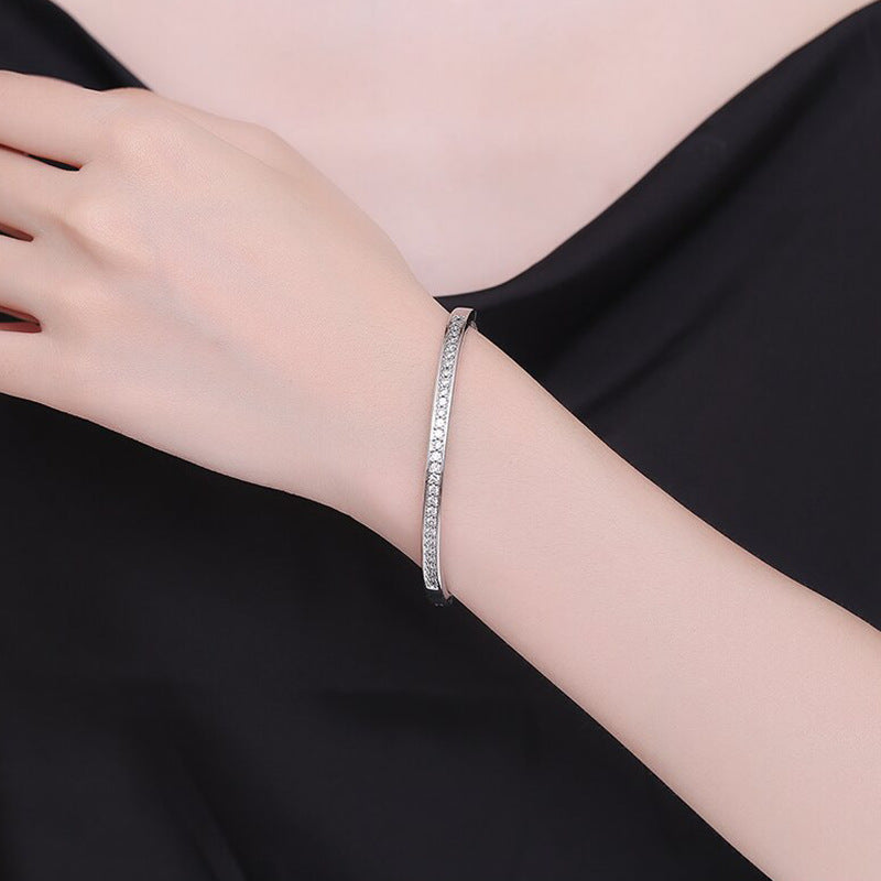 Silver bracelet on a person's wrist against a black background
