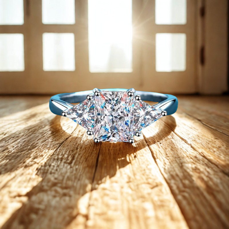 Noémie Moissanite Radiant Cut with triangle side stones ring on a wooden surface with sunlight filtering through