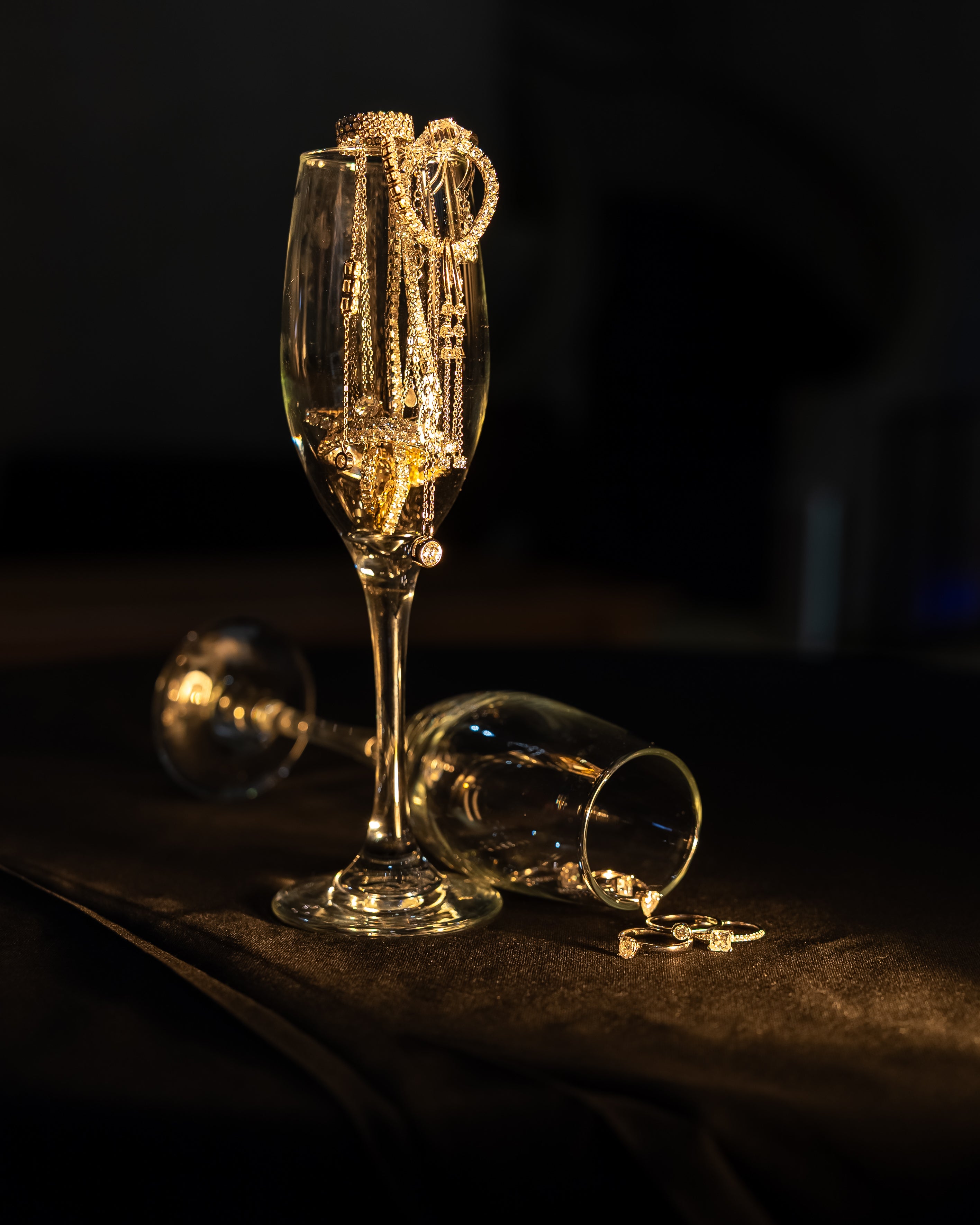 Prism and Pearl Jewellery draped over a champagne glass on a dark background