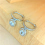 Silver hoop earrings with 1ct bezel set moissanites dangling off a piece of wood