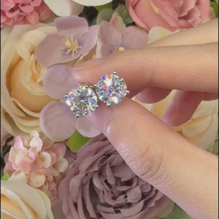 Video of moissanite earrings up close from all angles against a floral background
